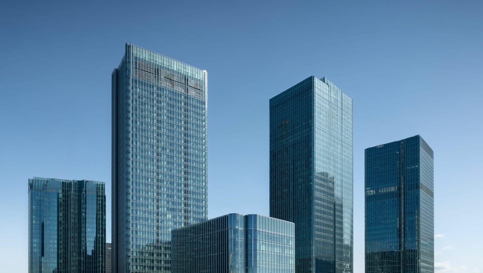 Looking up at modern glass high-rise towers against a clear sky